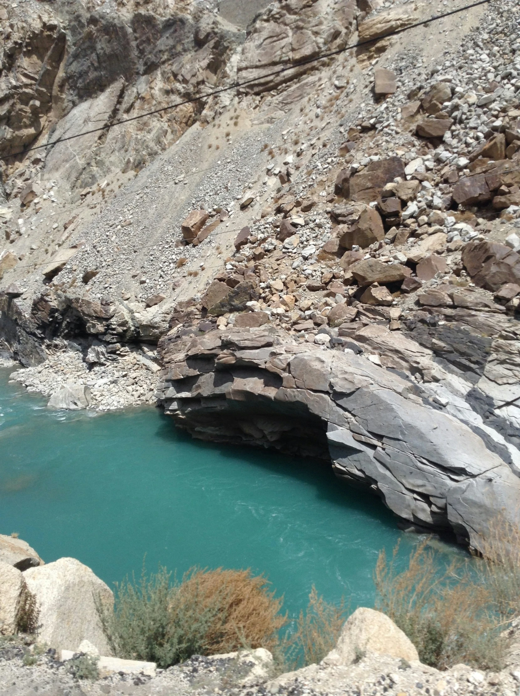 a very narrow cave and body of water near a rocky cliff