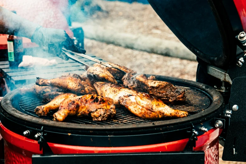 there are chicken wings cooking on an outdoor grill