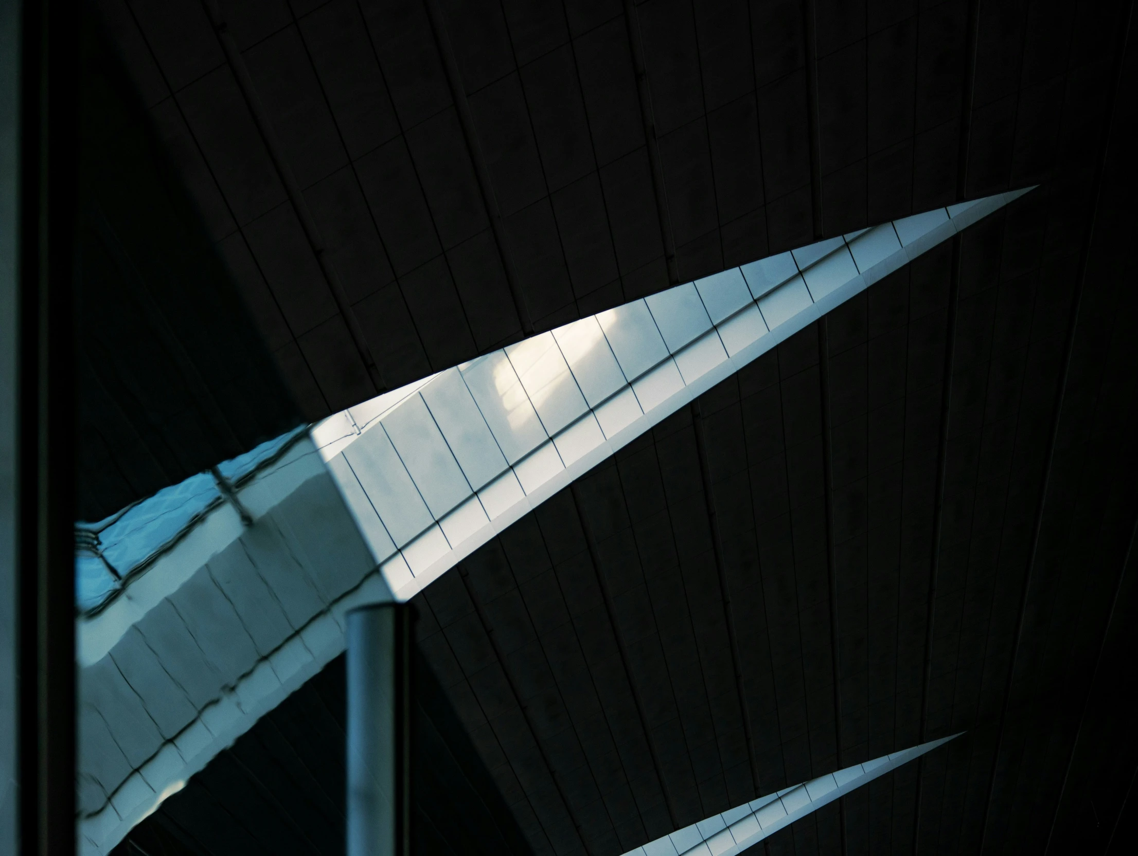 the triangular shaped window in a building with black walls