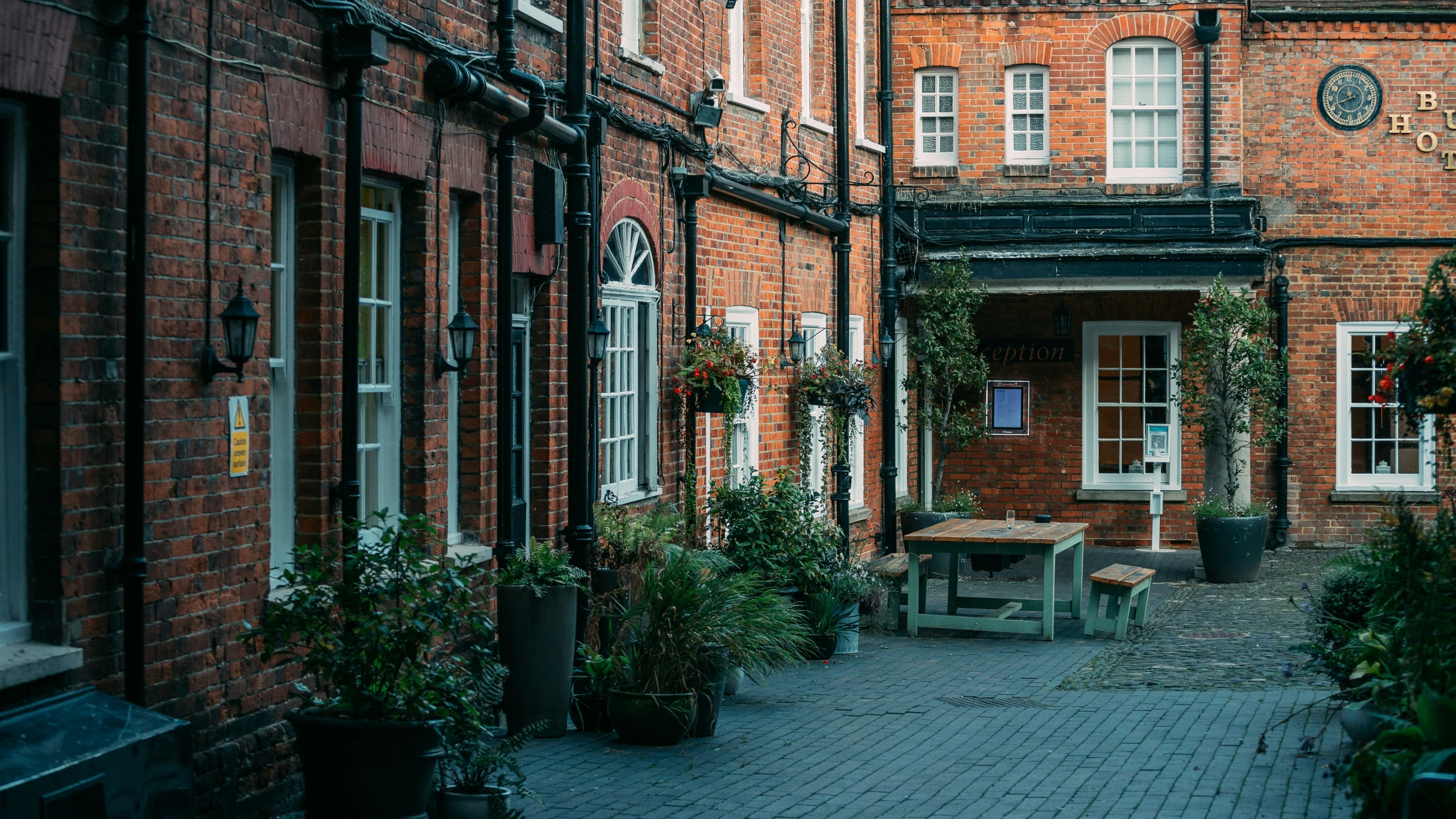 a brick building with a patio, bench and some plants