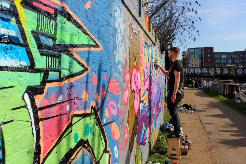 a person standing next to a wall covered in graffiti