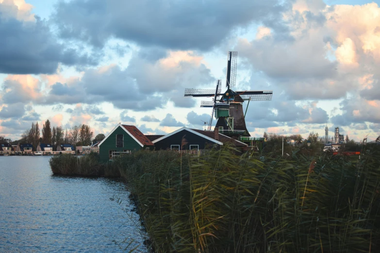 windmills next to a lake and houses on a cloudy day