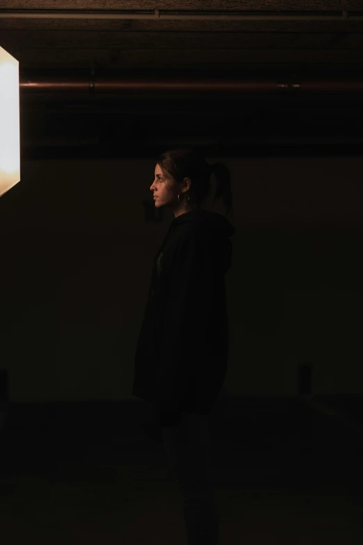 a woman standing in a dark room with a light on