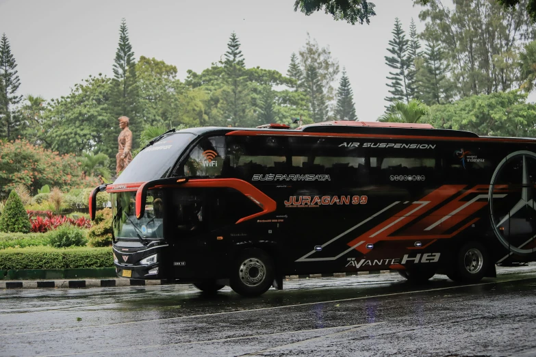 a black and orange bus is traveling down the road