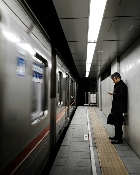 a person stands by a subway while on his cell phone