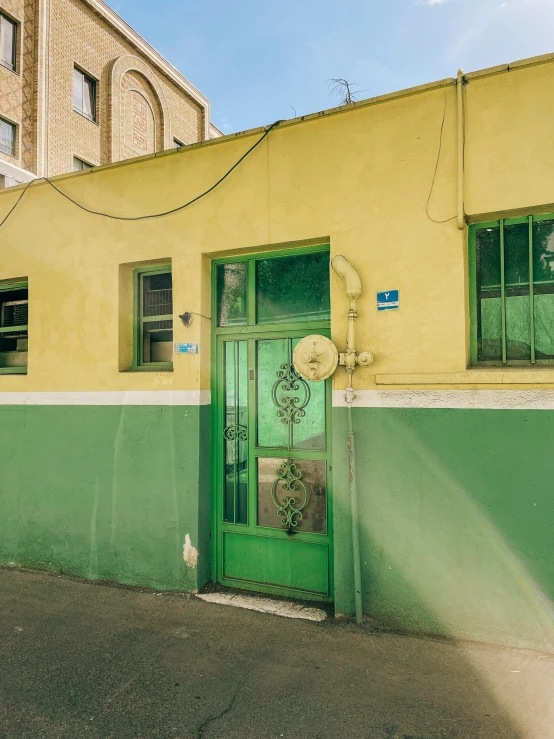 green doorway to a yellow building that is next to a road
