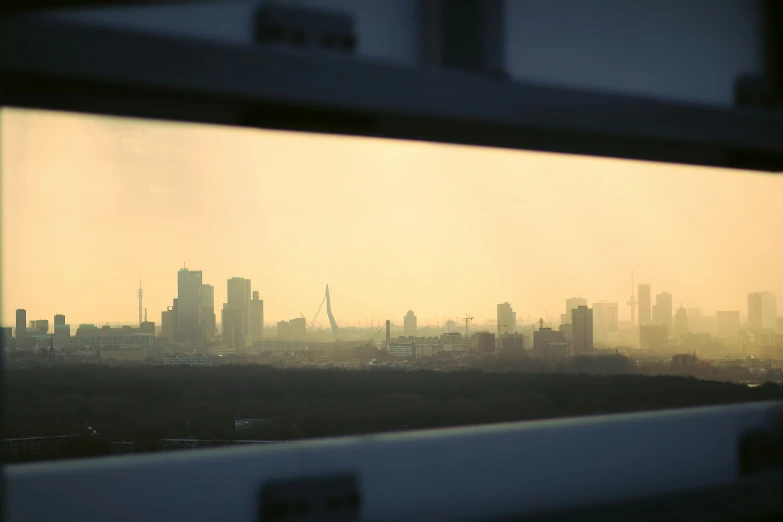 the city is silhouetted by this hazy view from a window