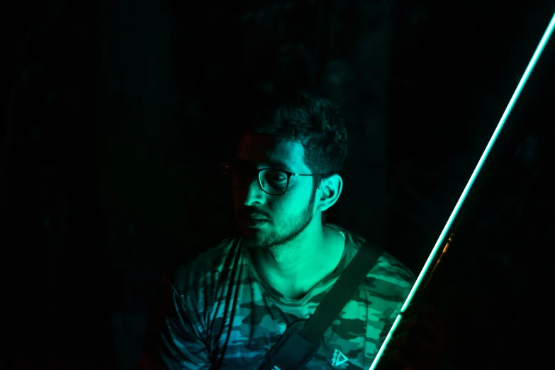 a man in the dark holds up a small light stick