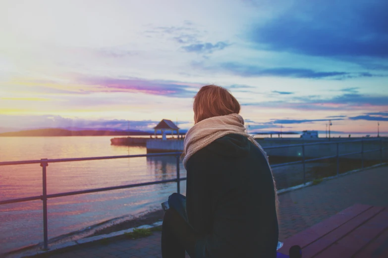 a person standing in front of a dock watching a boat go by