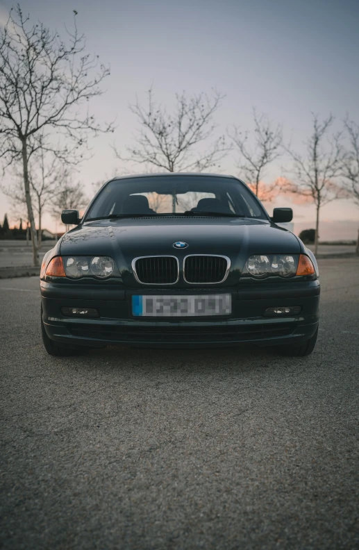 a black bmw is sitting outside in the parking lot