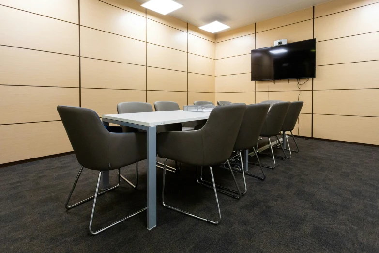 a table with a bunch of chairs in front of a flat screen