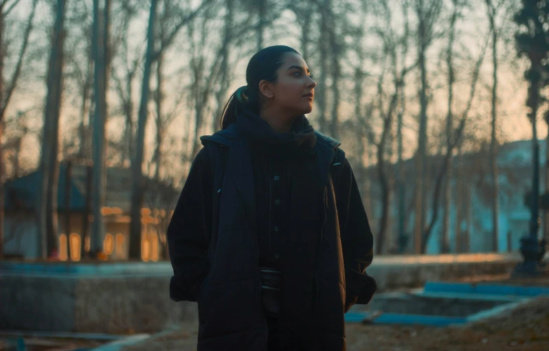 woman wearing winter coat in the woods at sunset