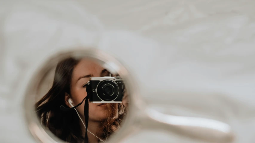 a woman in a white dress is holding a camera