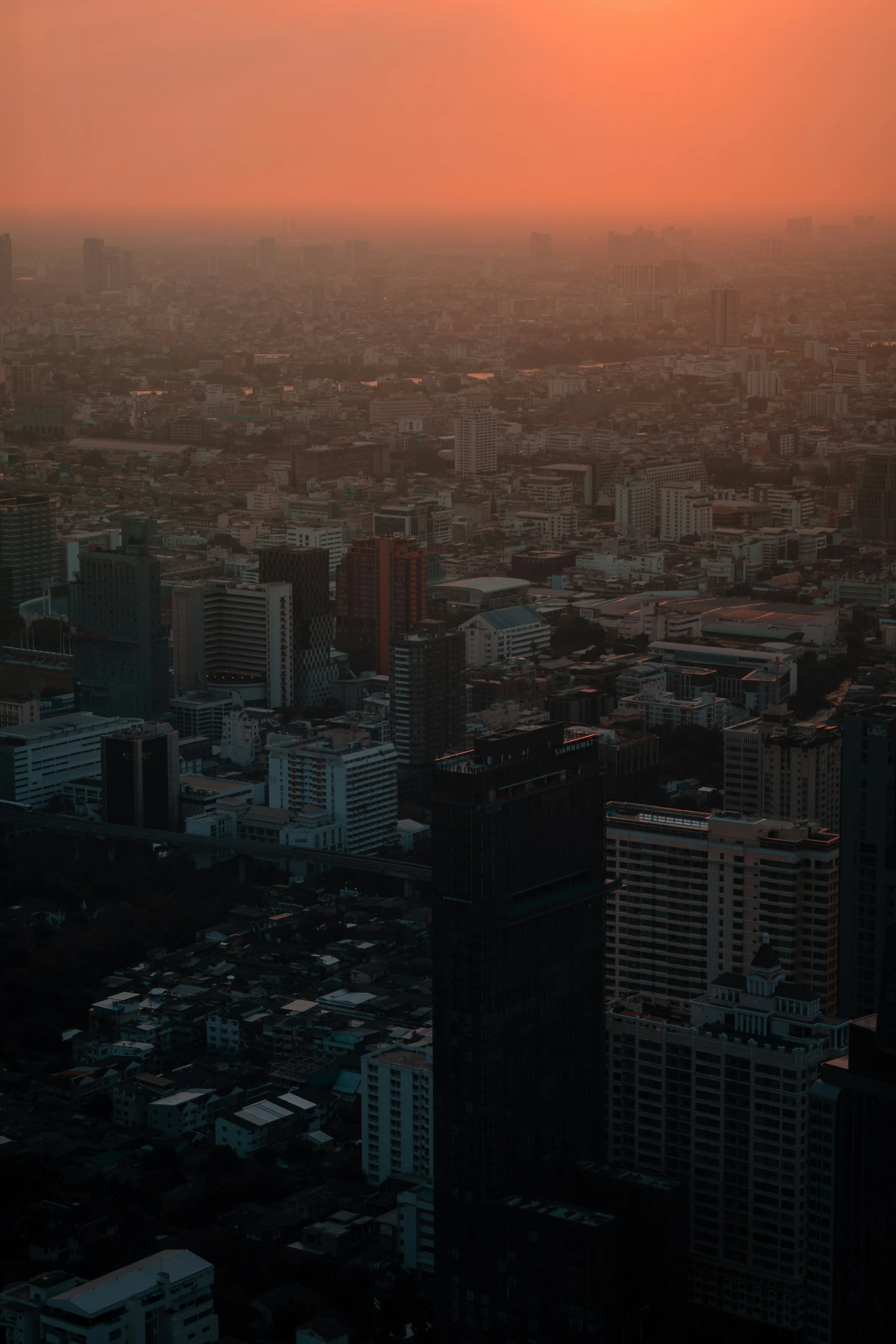 an airplane flies over a big city at sunset