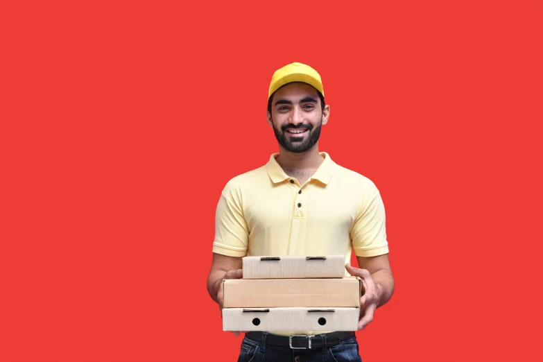 smiling delivery man with carton boxes in front of red backdrop