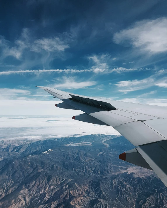 the wing of an airplane flies above the mountain