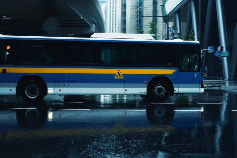 the bus is driving down the city street on a rainy day