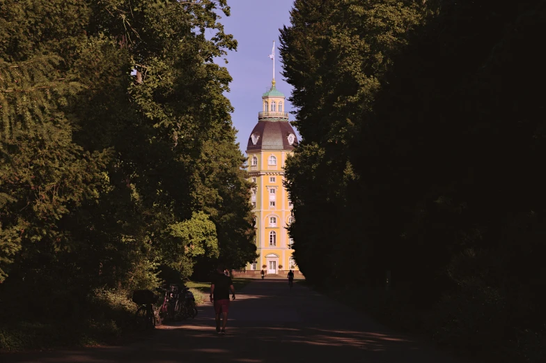 a group of people riding bikes down a path past a building