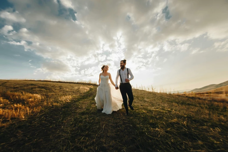 a newly married couple walk together in a field