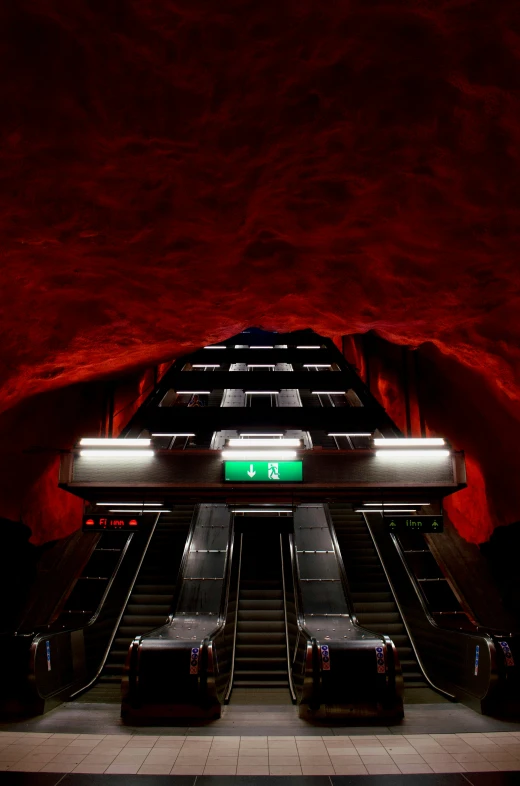 the escalators are lit at night and some people are standing at the end of one