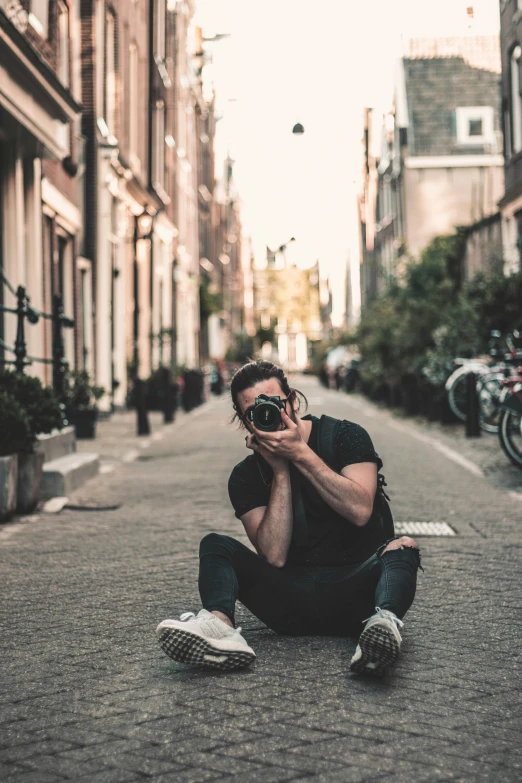 man taking a pograph on a city street