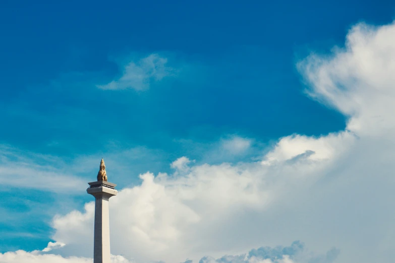 a monument with a cross atop it under a bright blue sky