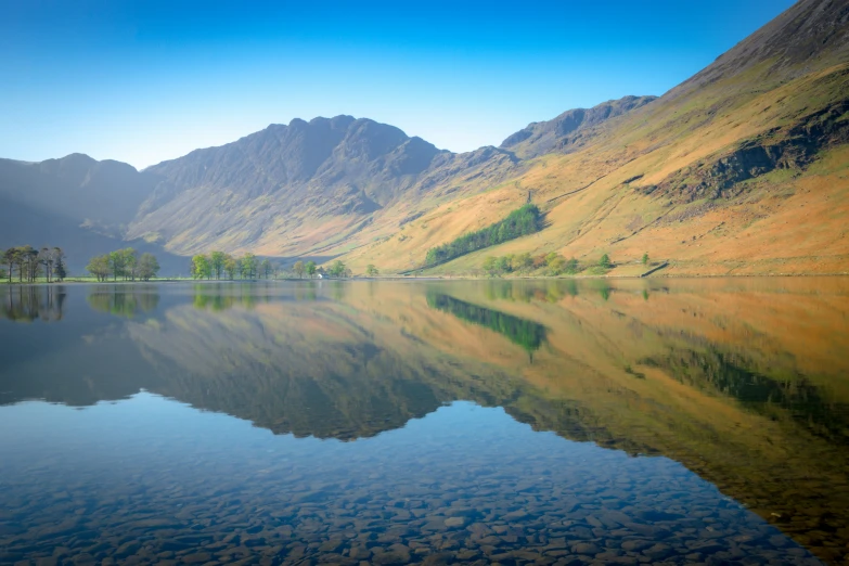 mountains reflecting in the water, with a lake and trees on each side