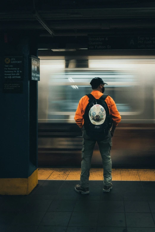 a man wearing a backpack waiting for a train