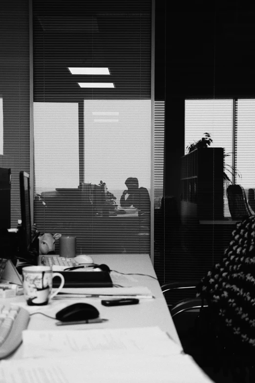 a desk with a pen and laptop next to two windows