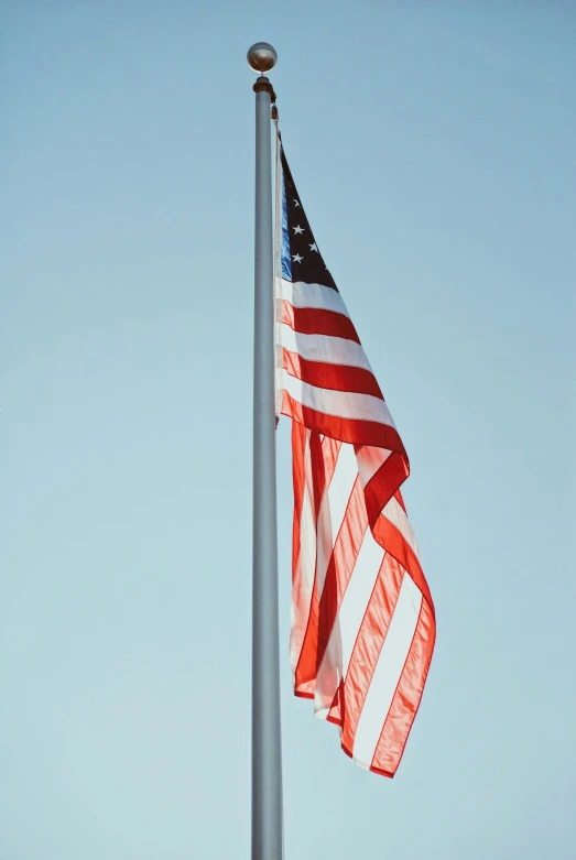 the american flag is flying in the blue sky