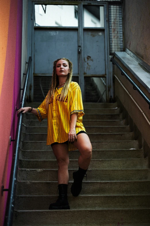 a woman wearing a yellow shirt is standing on some stairs