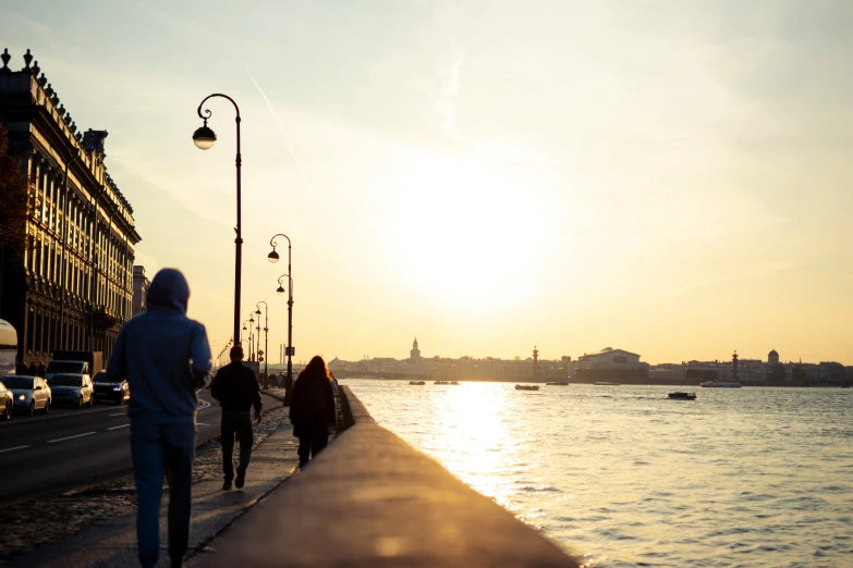 two people walk on a wall next to a body of water