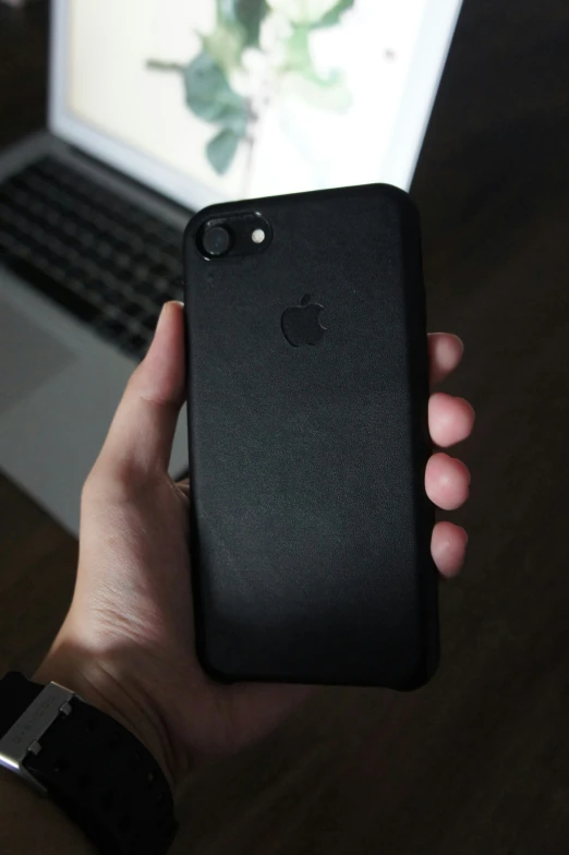 a person holding up an iphone in front of a computer