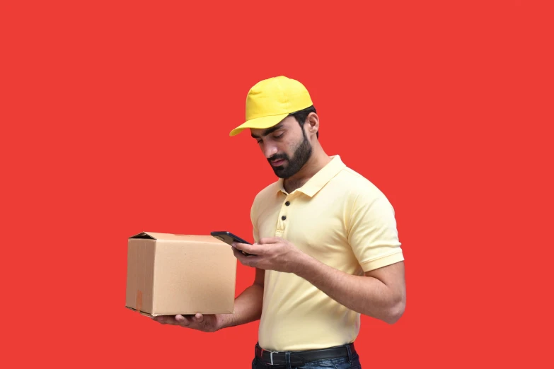 a man wearing a hardhat and yellow shirt holding a box