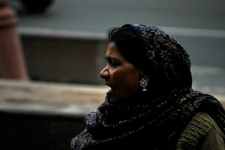 a woman wearing a scarf and earrings looks away