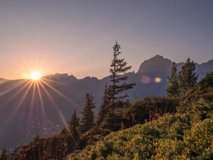 the sun is rising over the mountain side