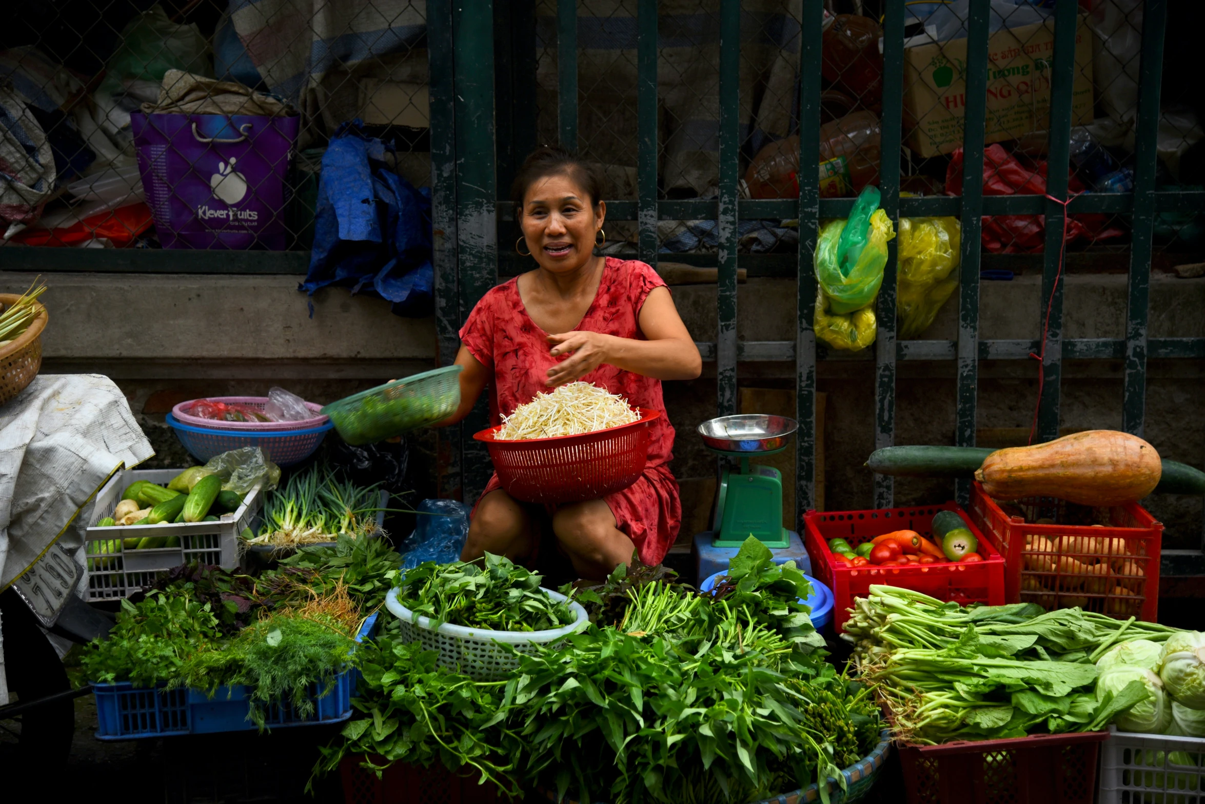 an asian woman smiles at the camera while she holds a basket of food in her hands