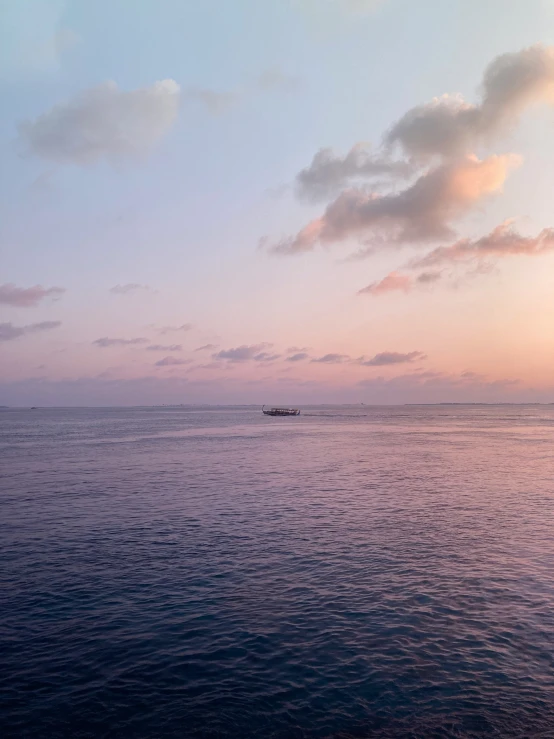 a boat sitting on top of the ocean during sunset