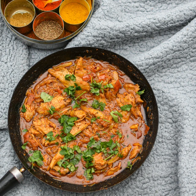 a pan of food sitting on a table next to three bowls with some condiments