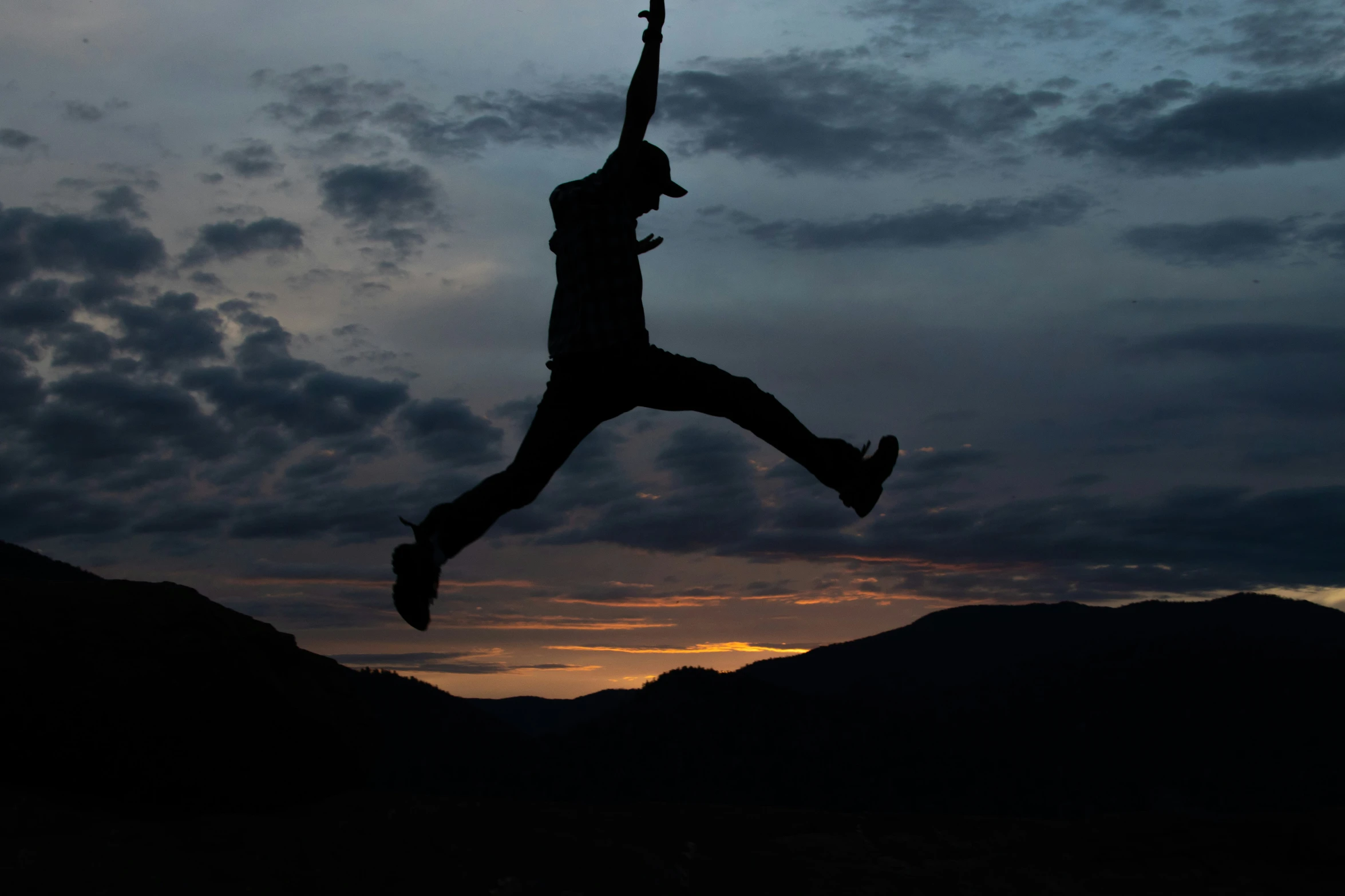 man in mid air catching up a frisbee during sunset