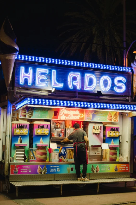 a man stands in front of a brightly lit neon neon food stand