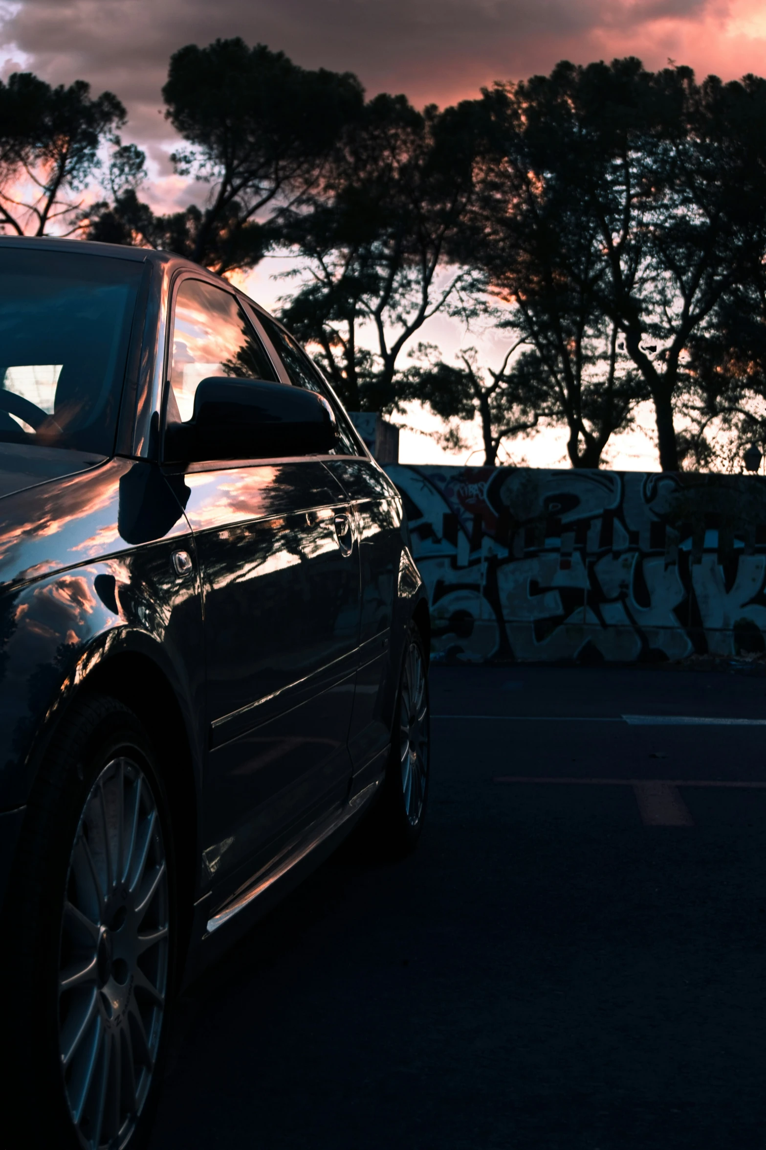 the car is parked by a wall with graffiti