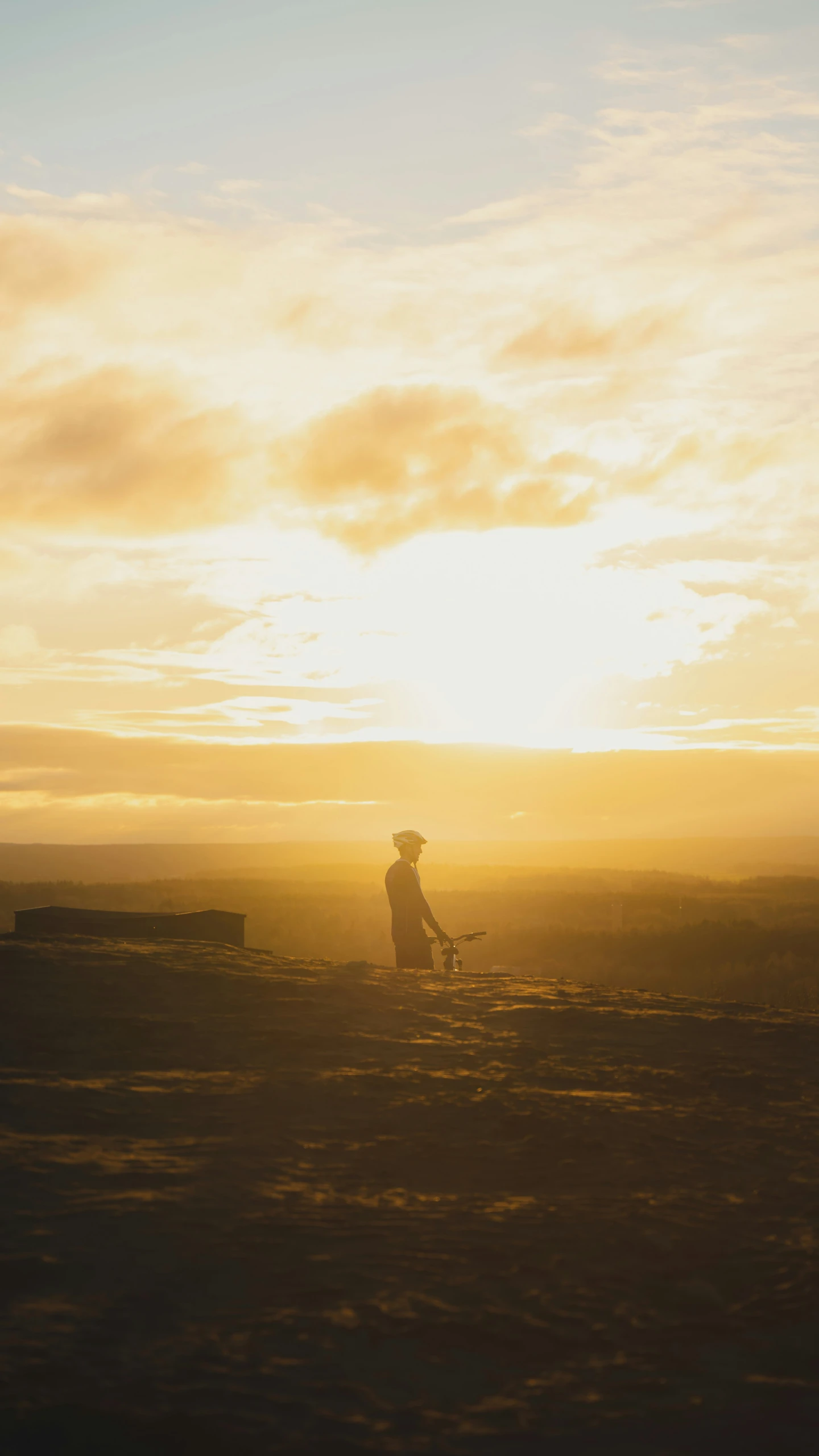 a silhouette of a person and an empty bench in front of the sun