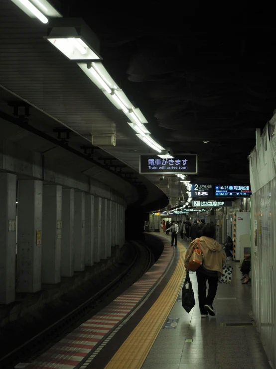 an underground train platform with people walking on the platform