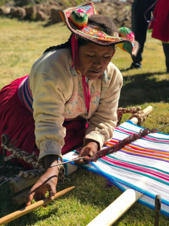 a woman in an ethnic dress bending over using a small piece of art