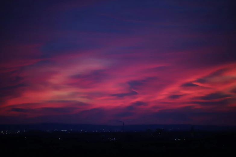 a purple sky filled with pink clouds above buildings