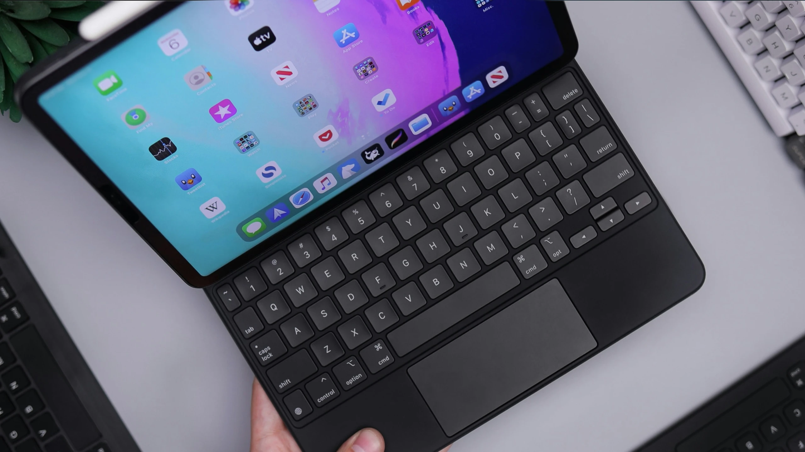 a man is holding a tablet on a keyboard