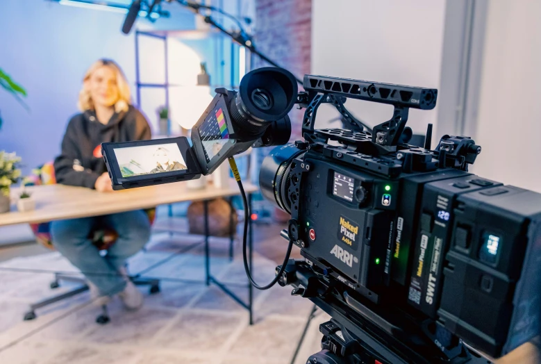 a camera taking pictures of a woman sitting at a table