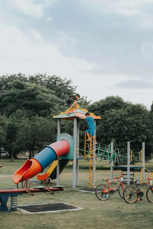 a playground with a colorful slide, bike's and swings