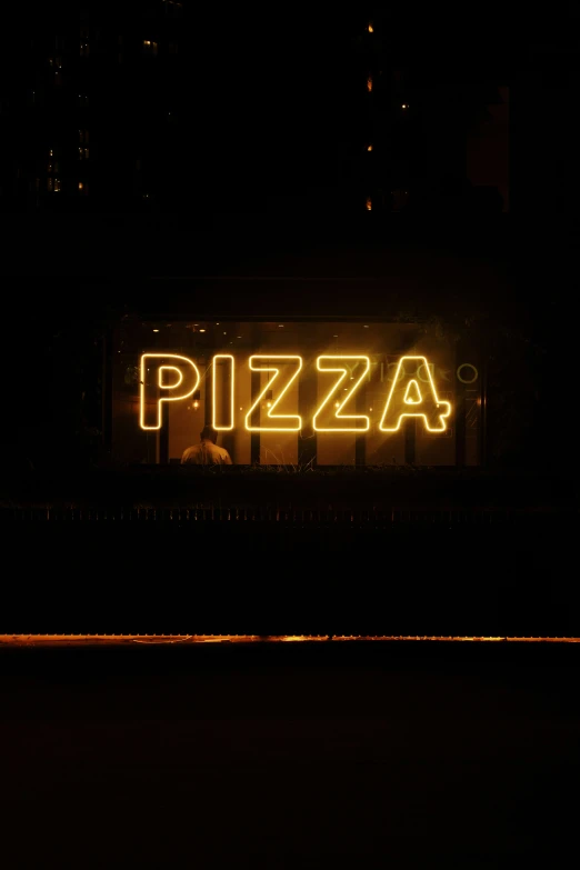 neon sign advertising pizza on street at night